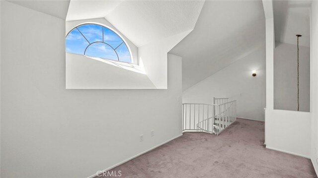 bonus room with light colored carpet and vaulted ceiling