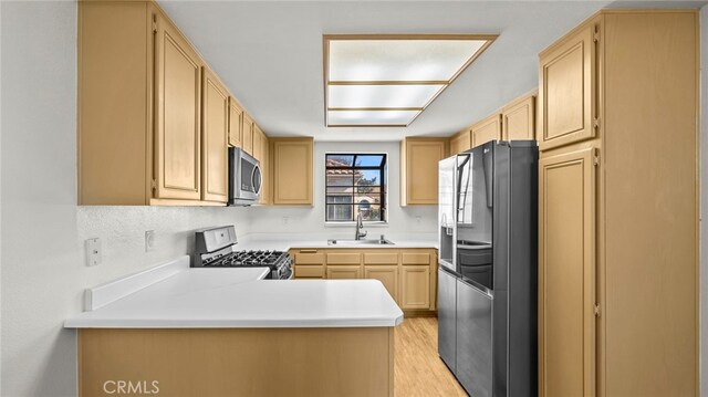 kitchen featuring light hardwood / wood-style floors, kitchen peninsula, sink, stainless steel appliances, and light brown cabinetry