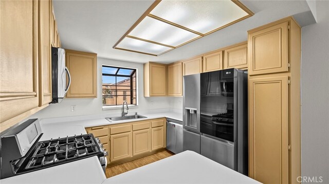 kitchen featuring light brown cabinetry, sink, stainless steel appliances, and light hardwood / wood-style floors