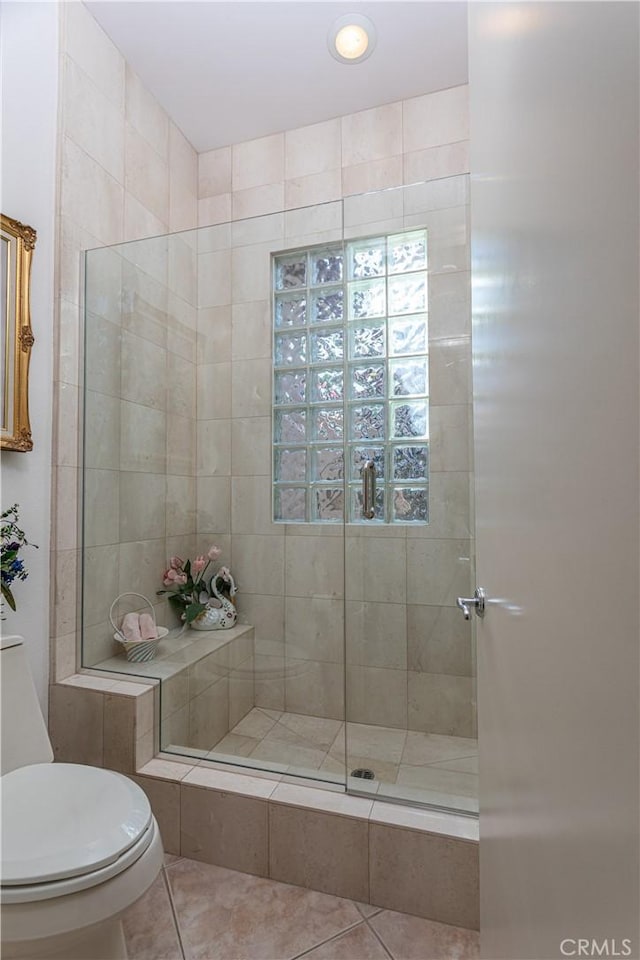 bathroom with tile patterned floors, toilet, and a tile shower