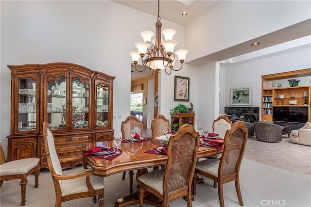 carpeted dining room with a towering ceiling and a chandelier