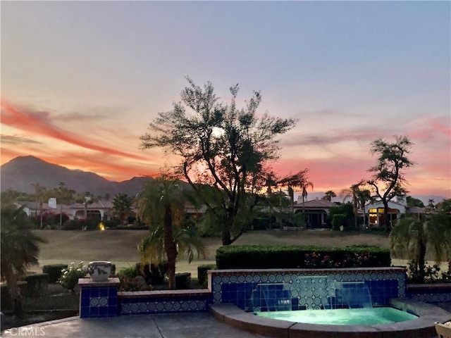 pool at dusk with pool water feature and a mountain view