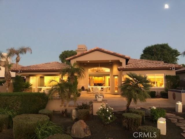 back house at dusk featuring a patio