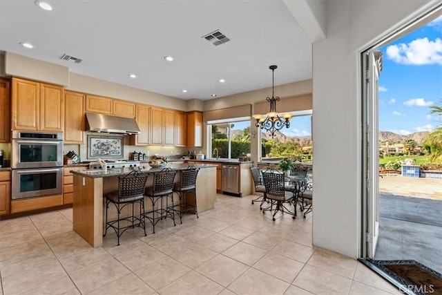 kitchen with a center island, an inviting chandelier, hanging light fixtures, dark stone countertops, and stainless steel appliances