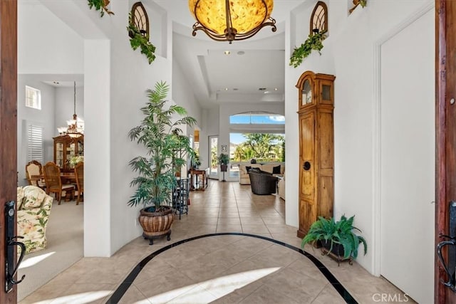 interior space featuring a notable chandelier, a towering ceiling, and light tile patterned floors