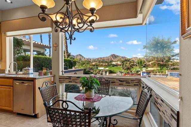 dining area with a notable chandelier, a mountain view, light tile patterned floors, and sink