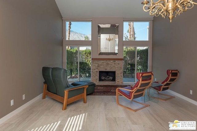 sitting room featuring a fireplace, a high ceiling, an inviting chandelier, and a healthy amount of sunlight