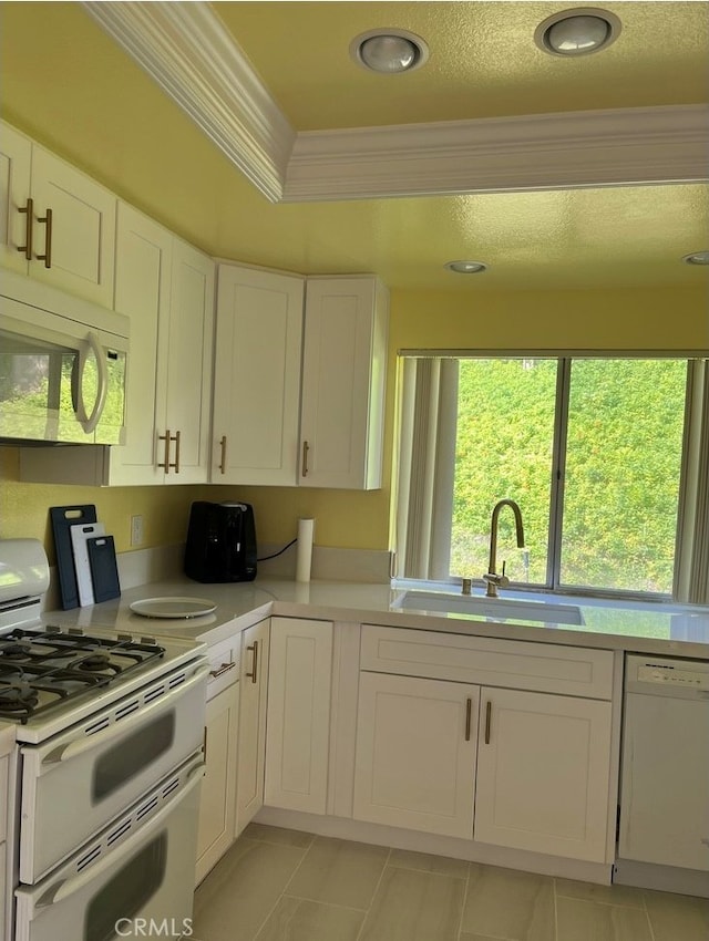 kitchen featuring sink, white appliances, white cabinets, and crown molding