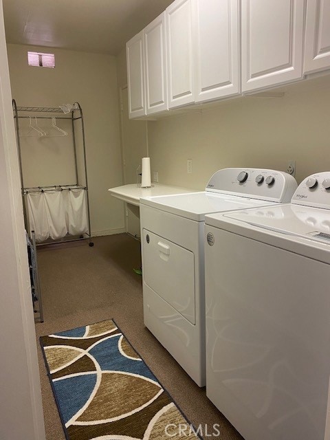 laundry area featuring independent washer and dryer, cabinets, and carpet