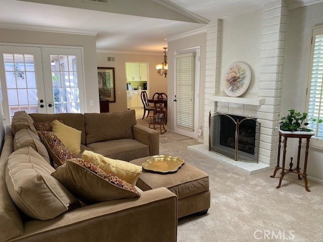 carpeted living room with a brick fireplace, a chandelier, crown molding, and french doors