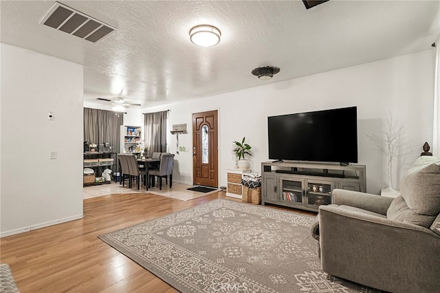 living room with ceiling fan, hardwood / wood-style flooring, and a textured ceiling