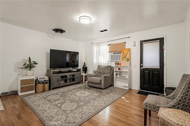 living room featuring cooling unit, a textured ceiling, and hardwood / wood-style floors