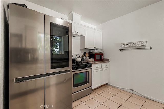 kitchen with light tile patterned flooring, appliances with stainless steel finishes, and white cabinetry