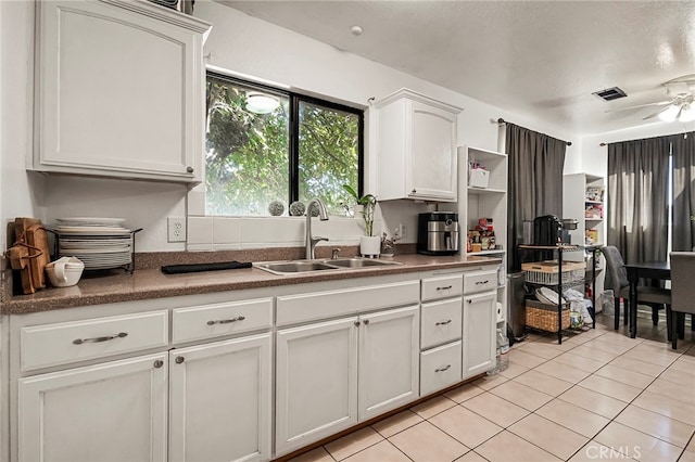 kitchen featuring light tile patterned floors, white cabinetry, sink, and ceiling fan