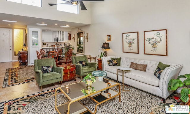 living room with a towering ceiling, ceiling fan, and tile patterned floors