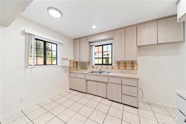 kitchen with a healthy amount of sunlight, light tile patterned flooring, decorative backsplash, and sink