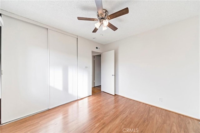 unfurnished bedroom with ceiling fan, wood-type flooring, a closet, and a textured ceiling