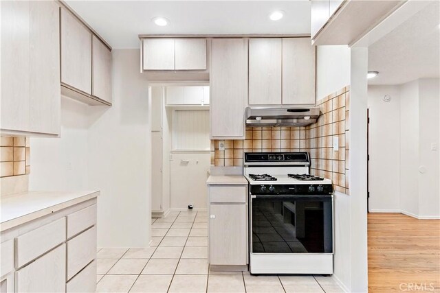 kitchen featuring gas range gas stove, backsplash, and light tile patterned floors