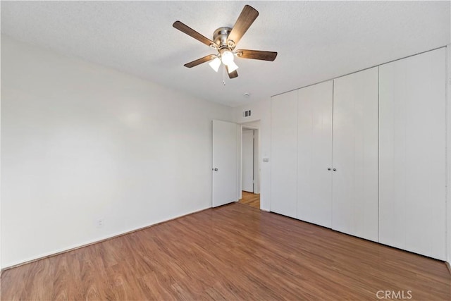 unfurnished bedroom featuring ceiling fan, wood-type flooring, and a closet