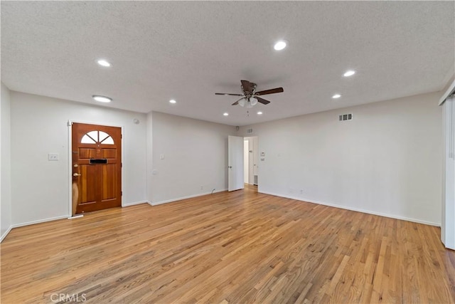 unfurnished living room with ceiling fan, a textured ceiling, and light hardwood / wood-style flooring