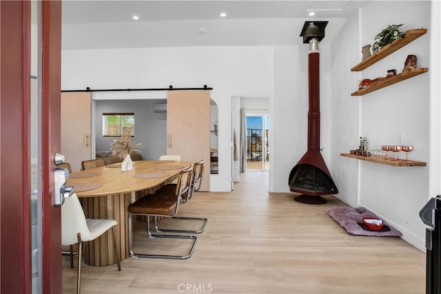 dining room with a barn door and light hardwood / wood-style flooring