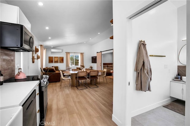 kitchen featuring appliances with stainless steel finishes, vaulted ceiling, white cabinetry, backsplash, and an AC wall unit