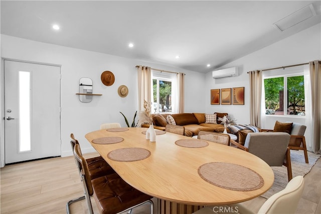 dining space with lofted ceiling, light hardwood / wood-style flooring, and a wall unit AC