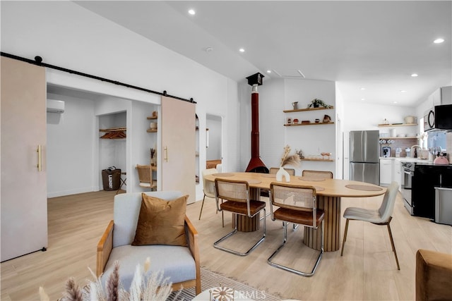 dining space featuring a barn door, light wood-type flooring, vaulted ceiling, and a wall unit AC