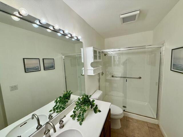 bathroom featuring toilet, vanity, tile patterned floors, and walk in shower