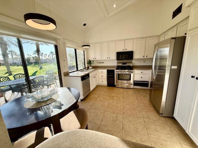 kitchen with stainless steel appliances, white cabinetry, and decorative light fixtures