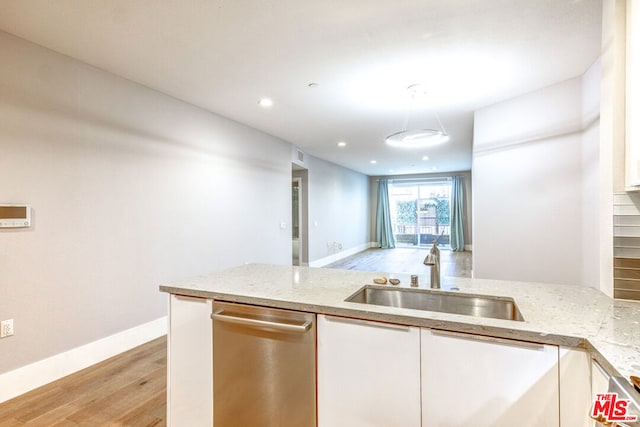 kitchen with white cabinets, sink, stainless steel dishwasher, light wood-type flooring, and light stone counters