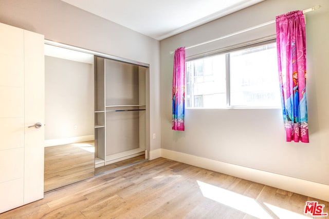 unfurnished bedroom with a closet and wood-type flooring