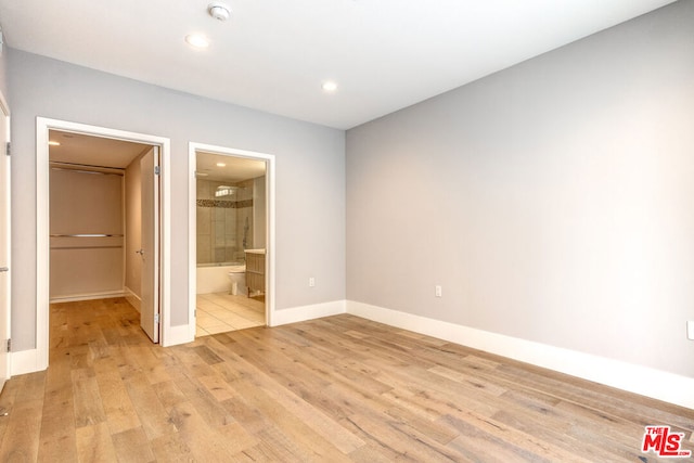 unfurnished bedroom with ensuite bathroom and light hardwood / wood-style flooring