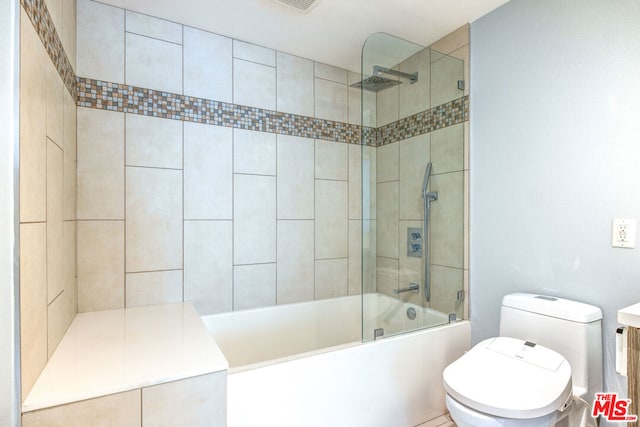 bathroom featuring toilet and tiled shower / bath