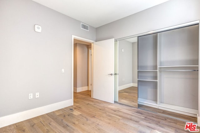 unfurnished bedroom with light hardwood / wood-style floors and a closet