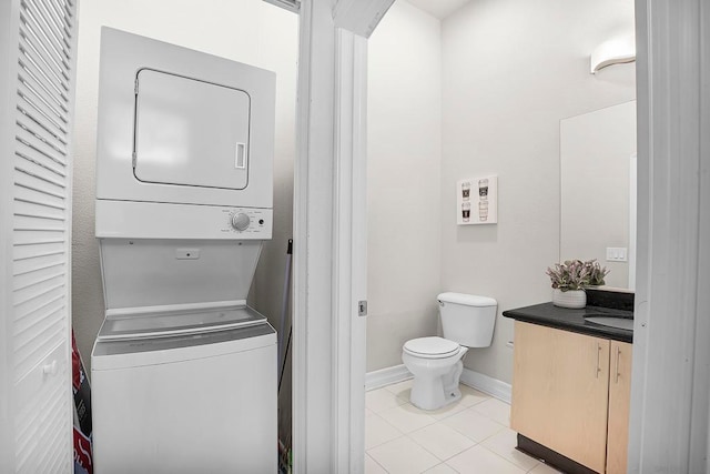 interior space featuring stacked washer / dryer, vanity, toilet, and tile patterned floors