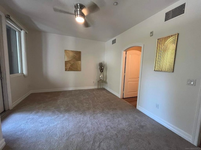 unfurnished room with dark carpet and ceiling fan