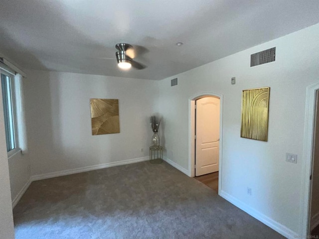 spare room with dark colored carpet and ceiling fan