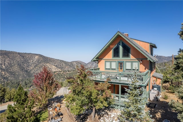 back of property with a mountain view and a balcony