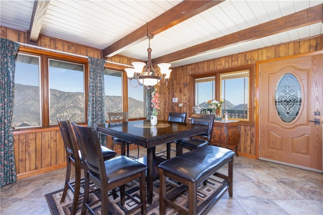 dining room featuring wooden walls, an inviting chandelier, beamed ceiling, and a mountain view