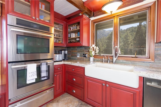 kitchen with decorative backsplash, stainless steel appliances, light stone counters, and sink