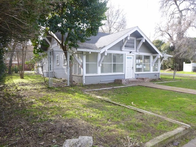 view of front of house with a sunroom and a front yard