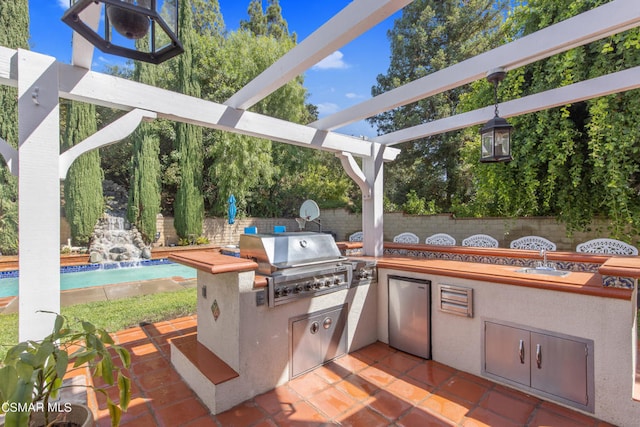 view of patio / terrace with a grill, pool water feature, sink, and exterior kitchen