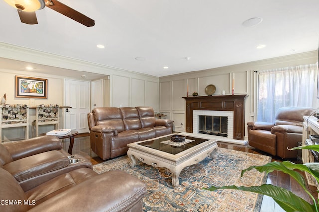 living room featuring a brick fireplace, ceiling fan, and ornamental molding