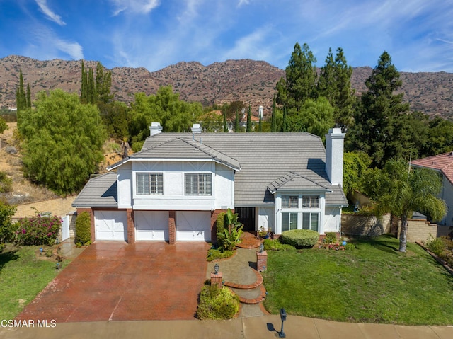 view of front of property featuring a mountain view, a front yard, and a garage