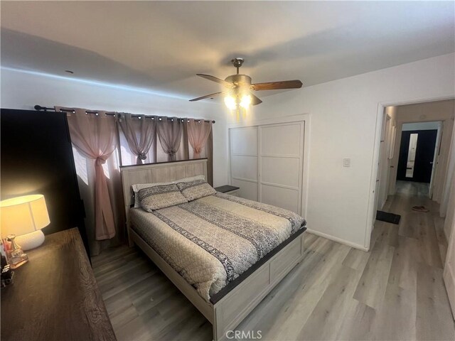 bedroom with ceiling fan, light hardwood / wood-style floors, and a closet