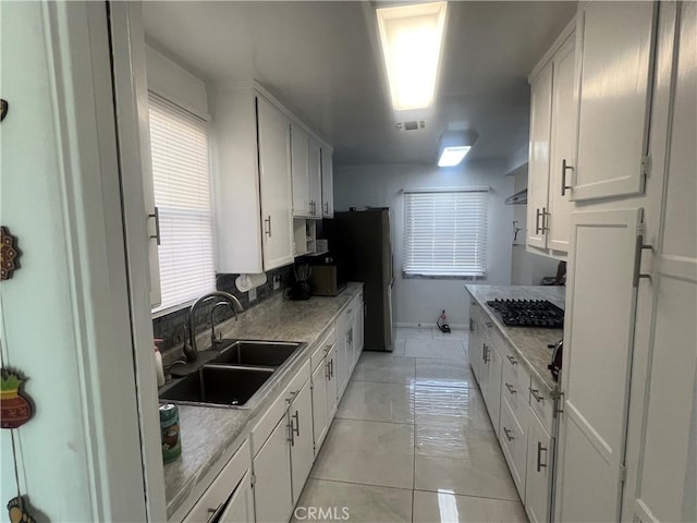 kitchen featuring white cabinets, stainless steel appliances, light stone countertops, and sink