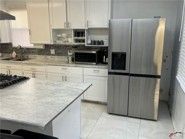 kitchen with white cabinets, stainless steel fridge, extractor fan, and sink