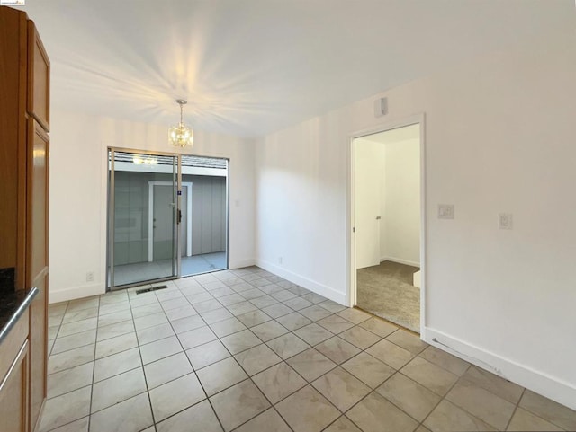 tiled empty room with an inviting chandelier