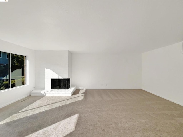 unfurnished living room featuring light colored carpet and a fireplace